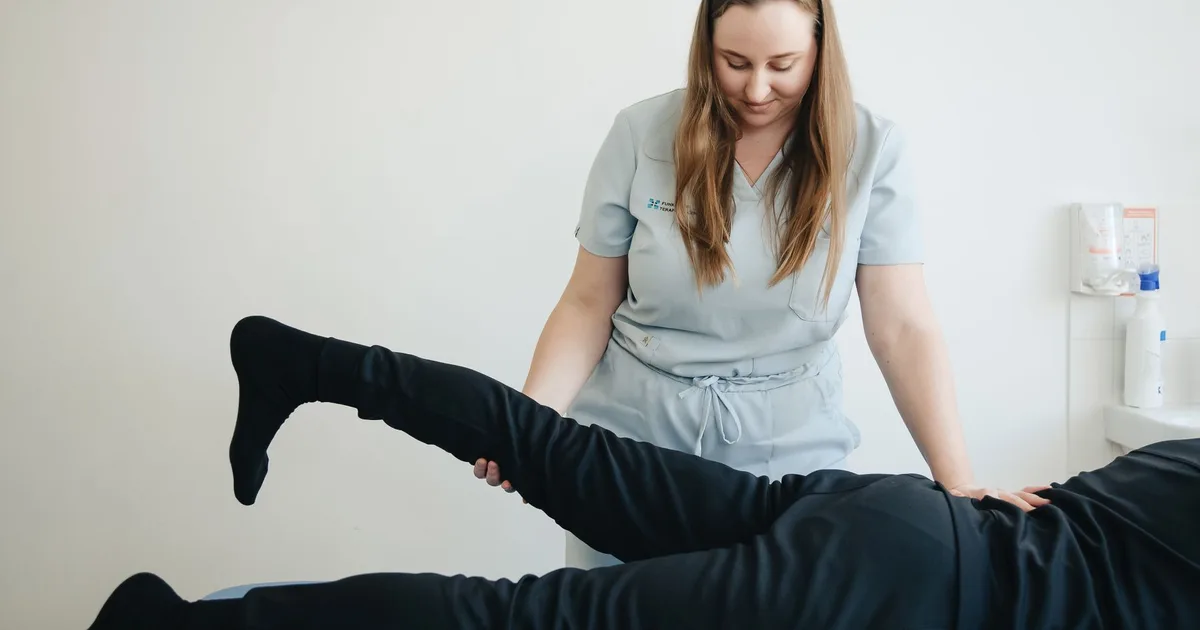 Fisioterapeuta acompanhando o movimento da perna de um paciente durante uma sessão
